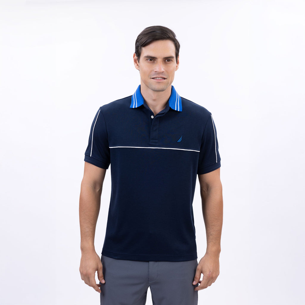 Hombre usando polo azul marino con vivos blancos y logo Nautica bordado, estilo náutico casual
