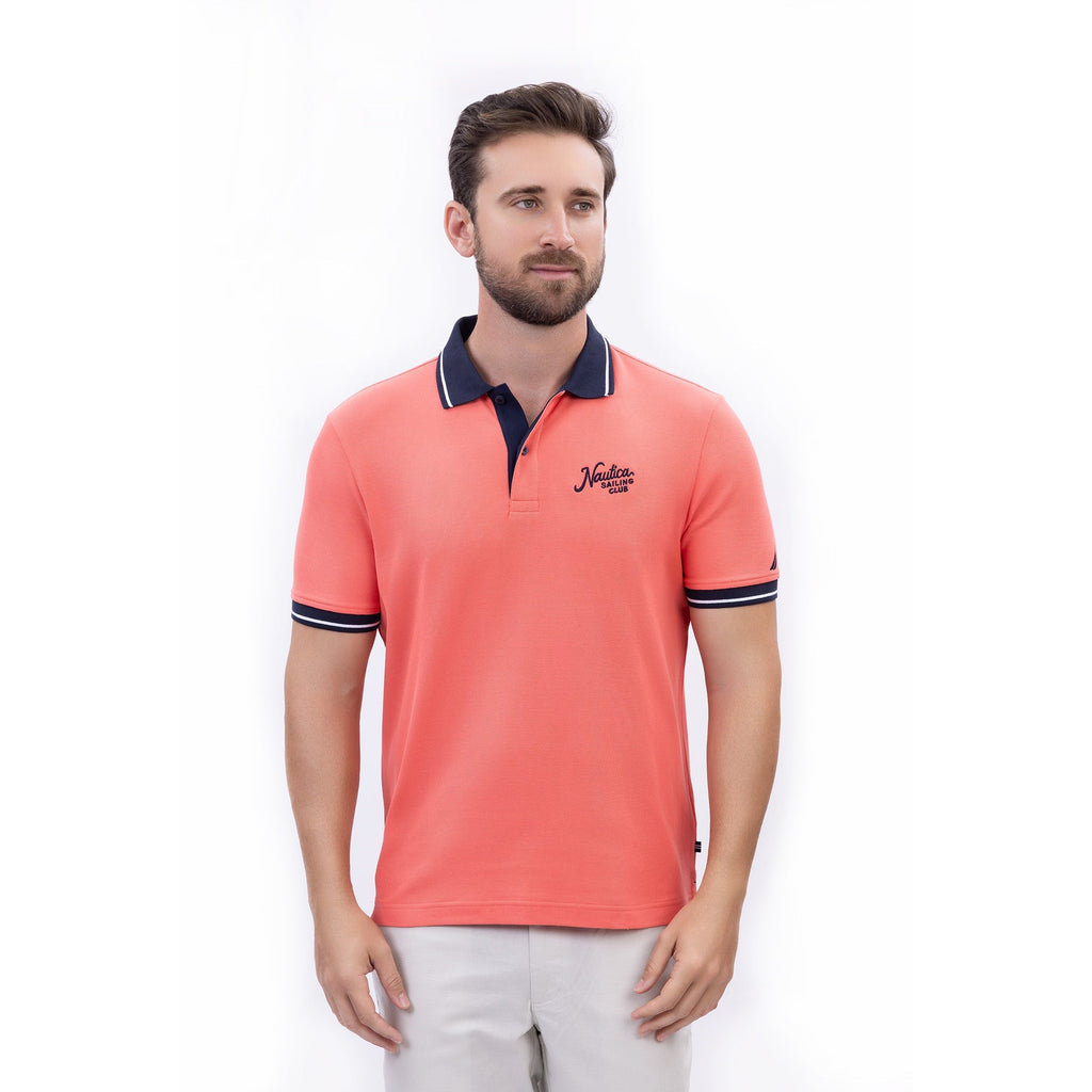 Hombre usando polo melón con cuello azul marino y logo Nautica, estilo clásico náutico