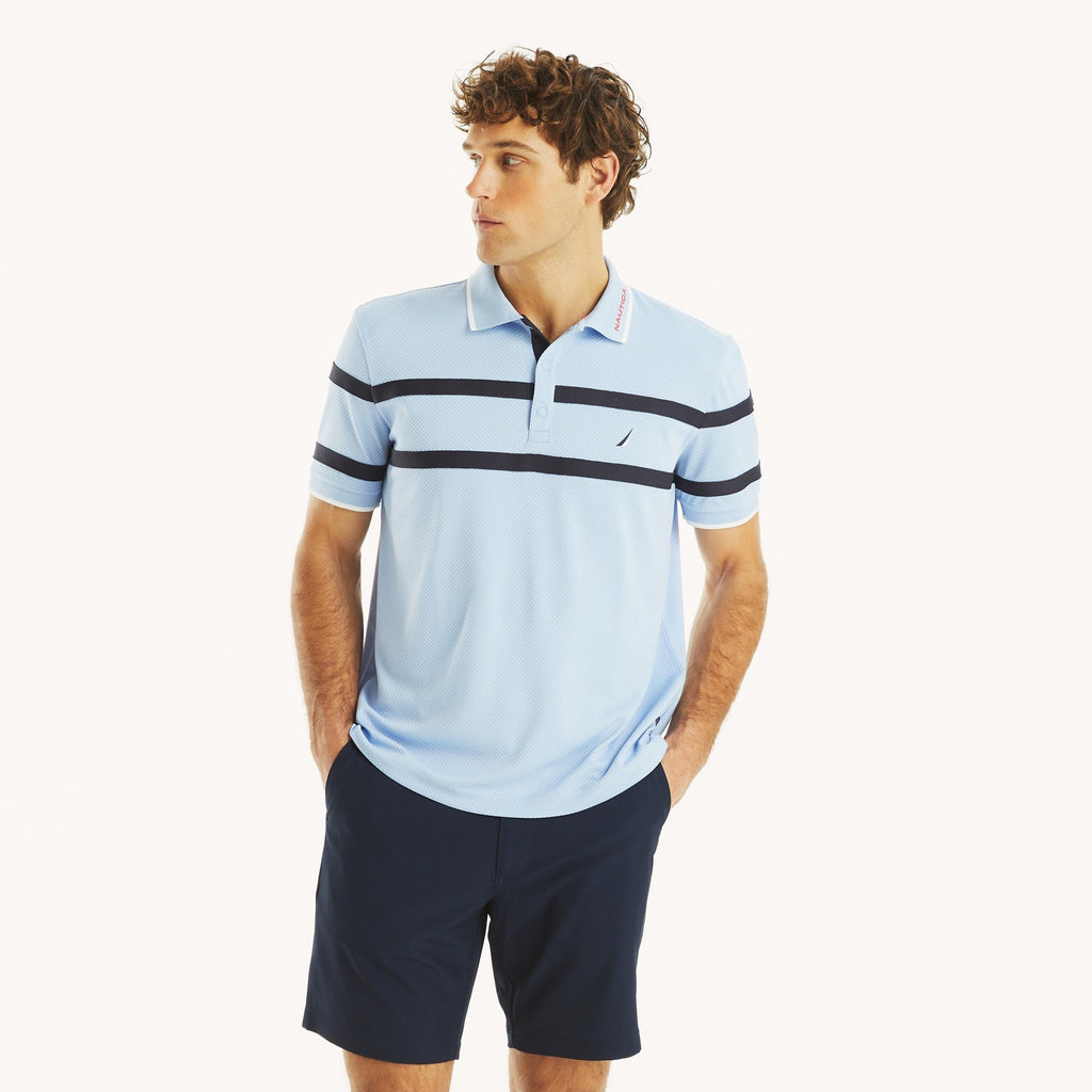 Hombre usando polo azul con franjas horizontales y logo Nautica, diseño deportivo y casual